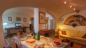 A dining area with a table set for a meal, a sofa, and a television in the background. - Belvilla by OYO Olmi (Casole d'Elsa)