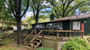A wooden deck with a staircase leading to a covered outdoor seating area. - Raper’s Hollow Waterfront Cabin (Eucha)