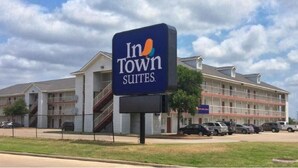 Un hotel con un letrero que dice "In Town Suites" y un edificio de varios pisos con balcones.