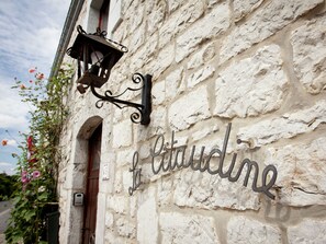 Ein Steinhaus mit einem Metallschild, auf dem 'La Cittadine' steht, und einem hängenden Laternenleuchter.
