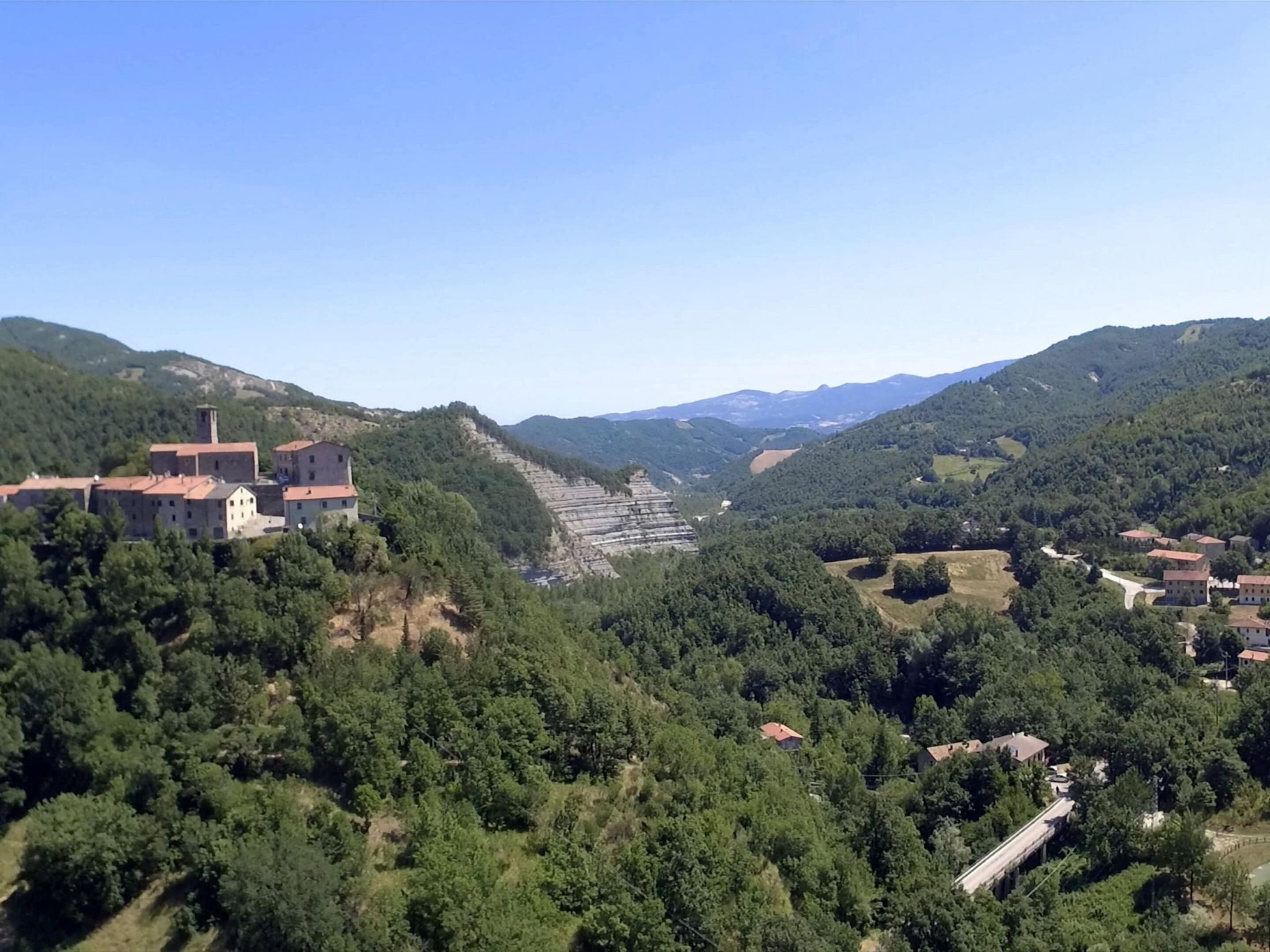 A mountainous landscape with a village featuring traditional buildings and a prominent church with a bell tower.