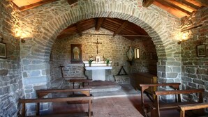 Une chapelle aux murs de pierre, dotée de bancs en bois, d’un crucifix et de statues religieuses.