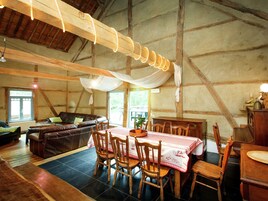 Un interior rústico de madera con comedor que incluye una mesa con mantel a cuadros, sillas de madera y una araña.