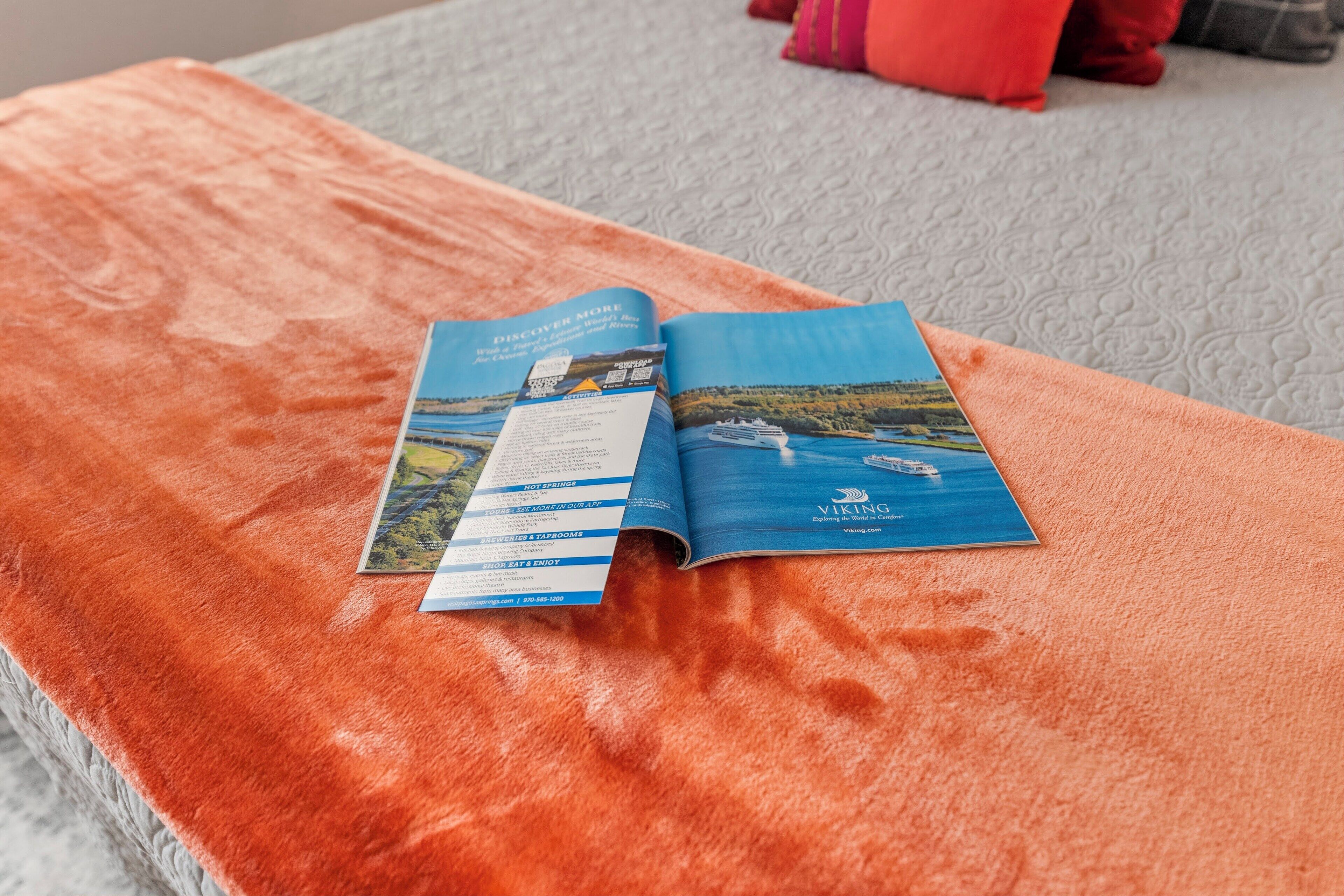 Eine Broschüre auf einem Bett mit Blick auf einen Fluss und ein Schiff.
