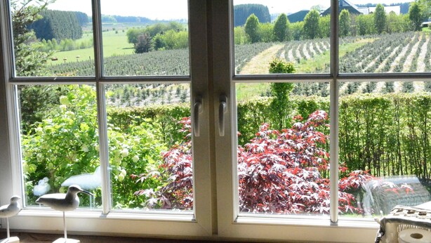 A room with large windows offering a view of a garden and fields. - Forest Cottage, Jehonville (Bertrix)