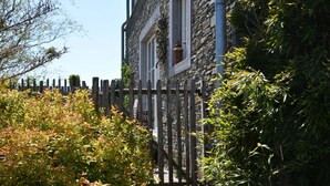 A stone building with a wooden fence and lush greenery. - Forest Cottage, Jehonville (Bertrix)