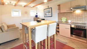 A compact kitchen with wooden beams, a dining area with a table and chairs, a sofa, and a small window. - Schone Ferienwohnung in Stellshagen mit Garten (Damshagen)