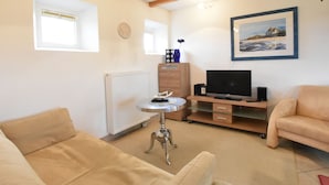 A cozy living room with a beige sofa, a small round table, a TV, and a painting on the wall. - Schone Ferienwohnung in Stellshagen mit Garten (Damshagen)