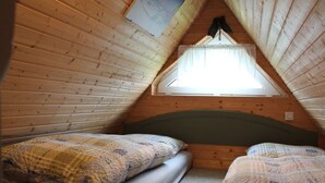 A small attic bedroom with two beds, wooden walls, a sloped ceiling, and a skylight. - Quaint Holiday Home in Schwaan near Lake (Schwaan)