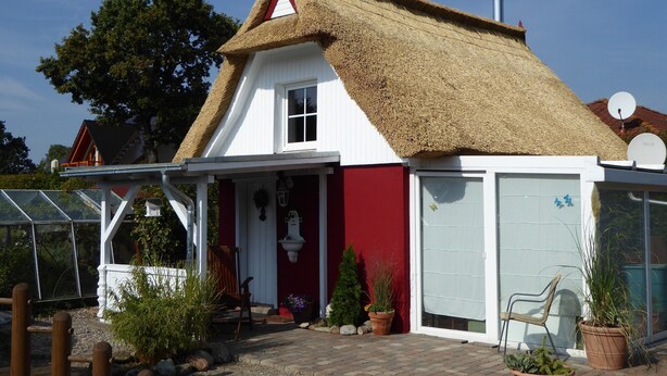 A house with a thatched roof, a white and red exterior, and a glass door. - Quaint Holiday Home in Schwaan near Lake (Schwaan)