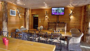 A rustic wooden interior with a long dining table, wicker chairs, and a television mounted on the wall. - Luxurious Villa in Stoumont With Sauna (Stoumont)