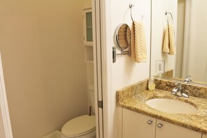 Ein Badezimmer mit Toilette, Waschbecken, Spiegel und Handtuchhalter.