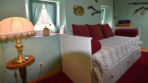 Een slaapkamer met een bed, lamp, radiator en een raam met gordijnen.