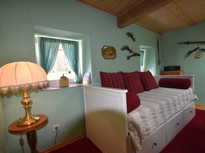 Ein Schlafzimmer mit Bett, Lampe, Heizkörper und einem fenster mit Vorhängen.