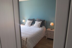 A bedroom with a bed, two bedside tables, and two lamps.