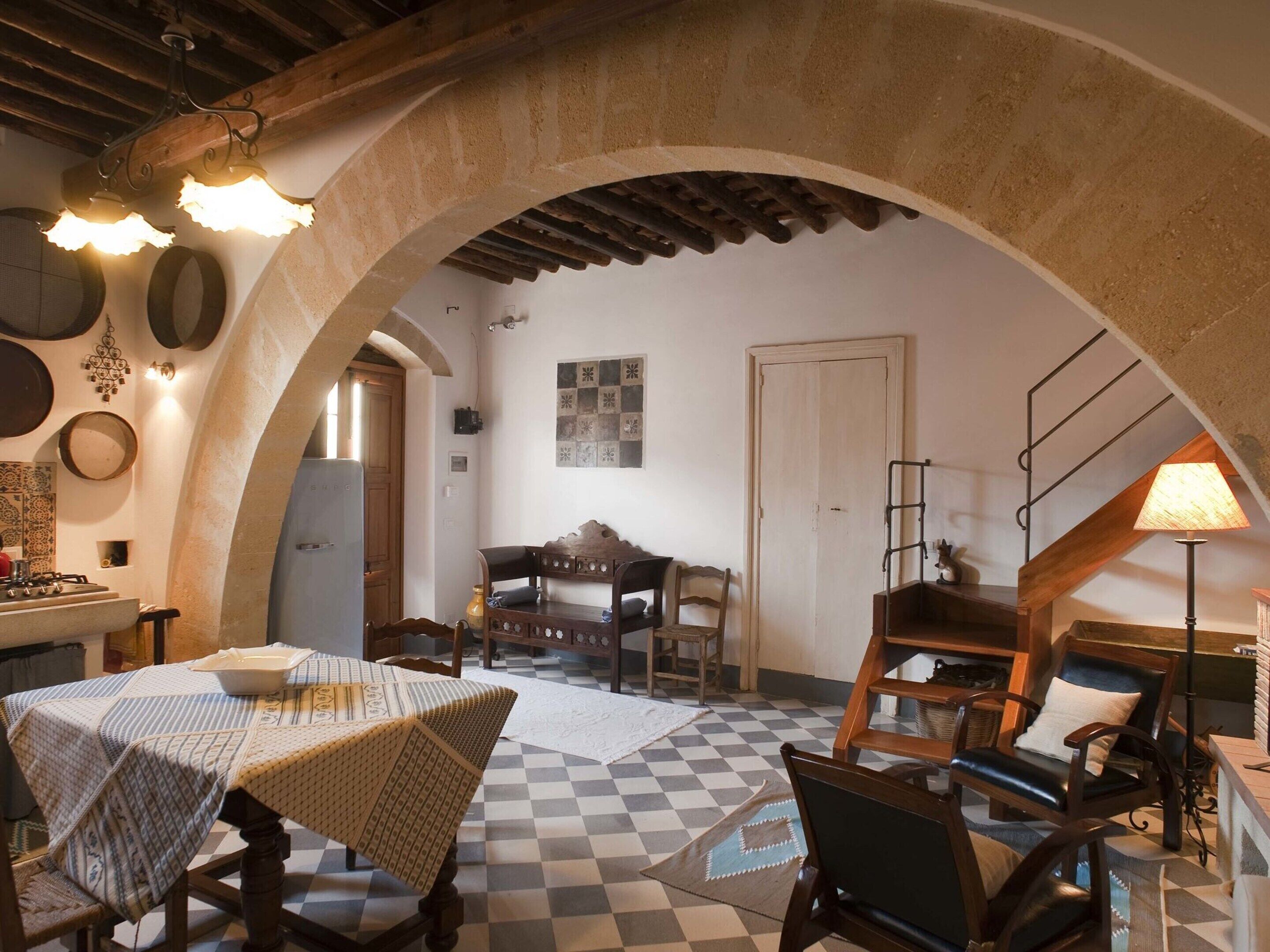 Une cuisine rustique avec un sol à carreaux, des meubles en bois et une arche en pierre.