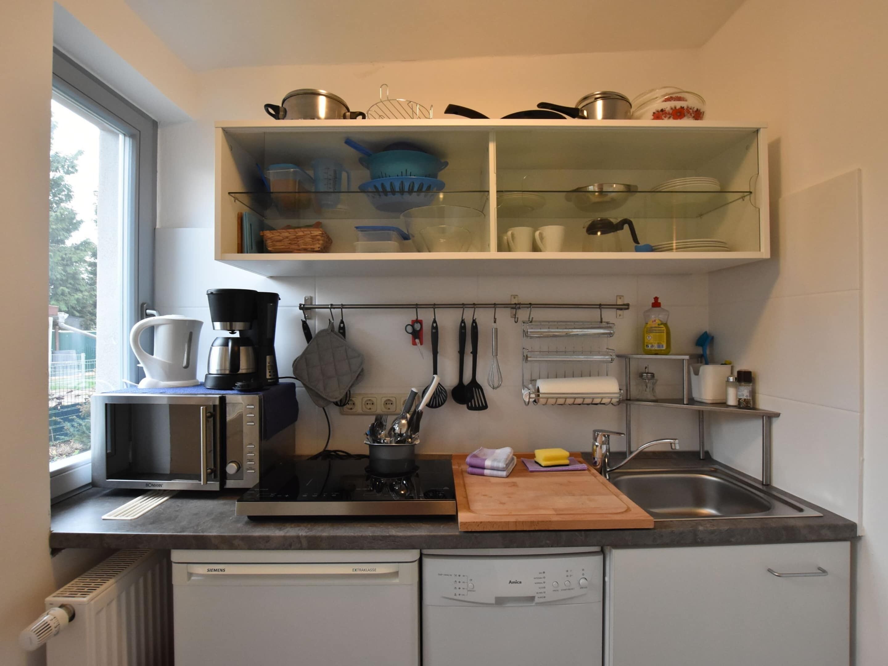 Une cuisine moderne équipée d’un four encastré, d’une machine à café et d’un lave-vaisselle.