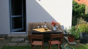 An outdoor patio with a table set for two, a wooden bench, and a potted plant. - Lavish Apartment in Klütz near Beach (Klütz)