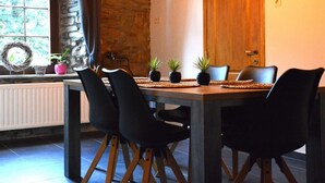 Un comedor con pared de piedra, puerta de madera y ventana con vistas a árboles.