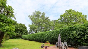 Een verzorgde tuin met een terras, tuinmeubilair en een vogelbad.