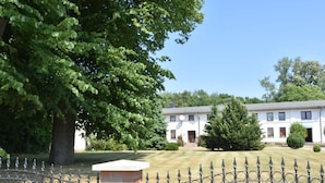 Een gebouw met twee verdiepingen, een fundering van baksteen en witte gevels.