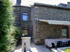 A stone building with a covered outdoor seating area, a fountain, and a lamp post. - Sauna Retreat in Herbeumont (Herbeumont)