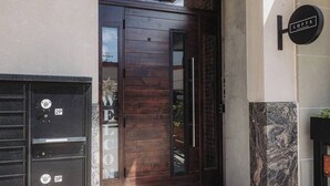 Une entrée moderne avec une porte en bois, un portail noir et une enseigne indiquant « LOFTS ».