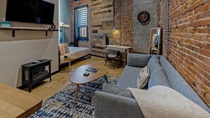 Un salon chaleureux avec un mur en briques, un téléviseur à écran plat, un canapé, une table basse et une cheminée.