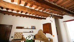 A rustic kitchen with exposed wooden beams, a tiled backsplash, and a hanging light fixture. - Adorable Farmhouse in Asciano (Asciano)