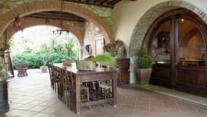 An outdoor patio with a rustic stone archway, wooden furniture, and potted plants. - Adorable Farmhouse in Asciano (Asciano)