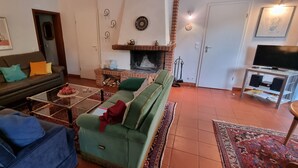 Una sala de estar con sofá, sillones, una mesita de centro, chimenea, televisor y mueble para televisión.