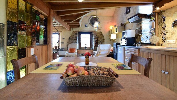 A rustic dining area with a wooden table, a basket of apples and nuts, and a stone wall in the background. - Holiday Home in Longueville (Durbuy)