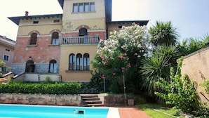 A two-story building with a swimming pool in the foreground. - Elegant Art Nouveau Villa With Private Pool Near the Lake (Desenzano del Garda)