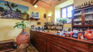 Eine Bar mit Holztresen, Regalen voller Flaschen, einem Fernseher und Wandgemälde.