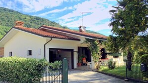 A two-story house with a red-tiled roof, a garage, and a small porch area with outdoor seating. - Villa in Northern Italy Near Borgo di Toppo (Travesio)