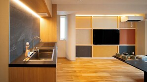 Une cuisine moderne équipée d’une cuisinière intégrée, d’un évier et d’un téléviseur à écran plat fixé au mur.
