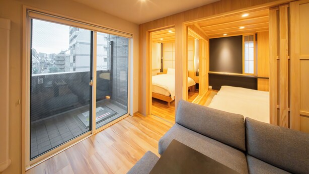Une chambre d’hôtel moderne dotée d’une porte-fenêtre coulissante donnant sur un balcon, d’un lit, d’un canapé et d’une petite table.