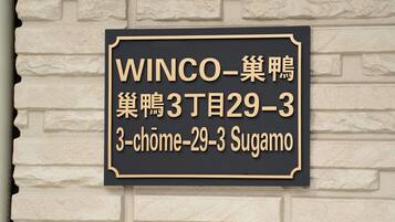 A black and gold sign with white text on a brick wall.