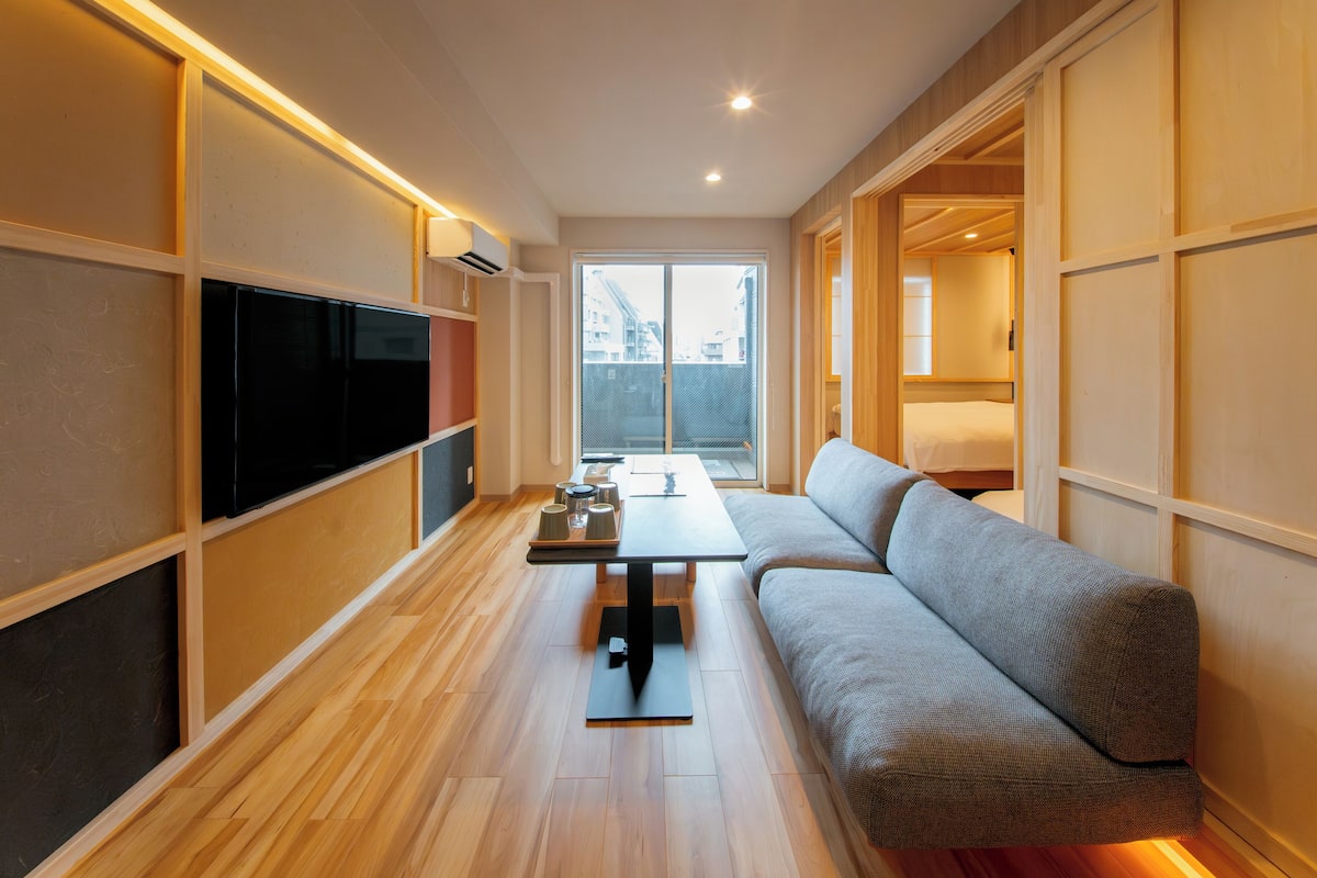 A modern living room with a sofa, a flat-screen TV, and a dining table.