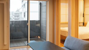 Une chambre dotée d’une porte-fenêtre coulissante donnant sur un balcon, d’un lit et d’une petite table.
