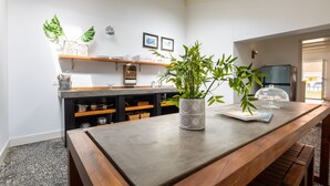 A modern kitchen with a wooden table, a potted plant, and a refrigerator.
