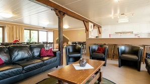 Un intérieur chaleureux avec un canapé en cuir, une table basse en bois et des fauteuils en cuir noir.