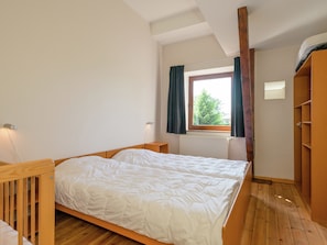 A bedroom with a wooden bed, a window with curtains, a radiator, and a wooden wardrobe. - Modern Cottage With Private Garden in Waimes (Waimes)