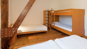 Une chambre de dortoir avec deux lits superposés, un plancher en bois et un plafond en pente.