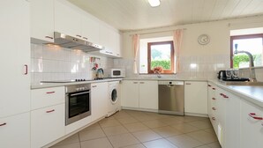 Une cuisine avec des meubles blancs, une cuisinière, un four, un four à micro-ondes et un lave-vaisselle.