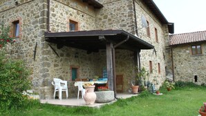 A stone building with a covered patio, outdoor seating, and potted plants. - Holiday Home in Mulazzo With Natural Pond (Mulazzo)