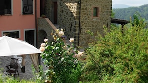 A stone building with a balcony, a pink wall, and a white umbrella. - Holiday Home in Mulazzo With Natural Pond (Mulazzo)