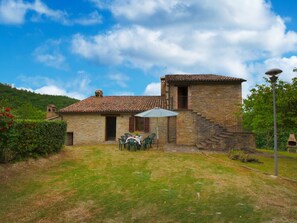 Situated in a lush landscape, this house features a small staircase, patio area, and well-maintained lawn.