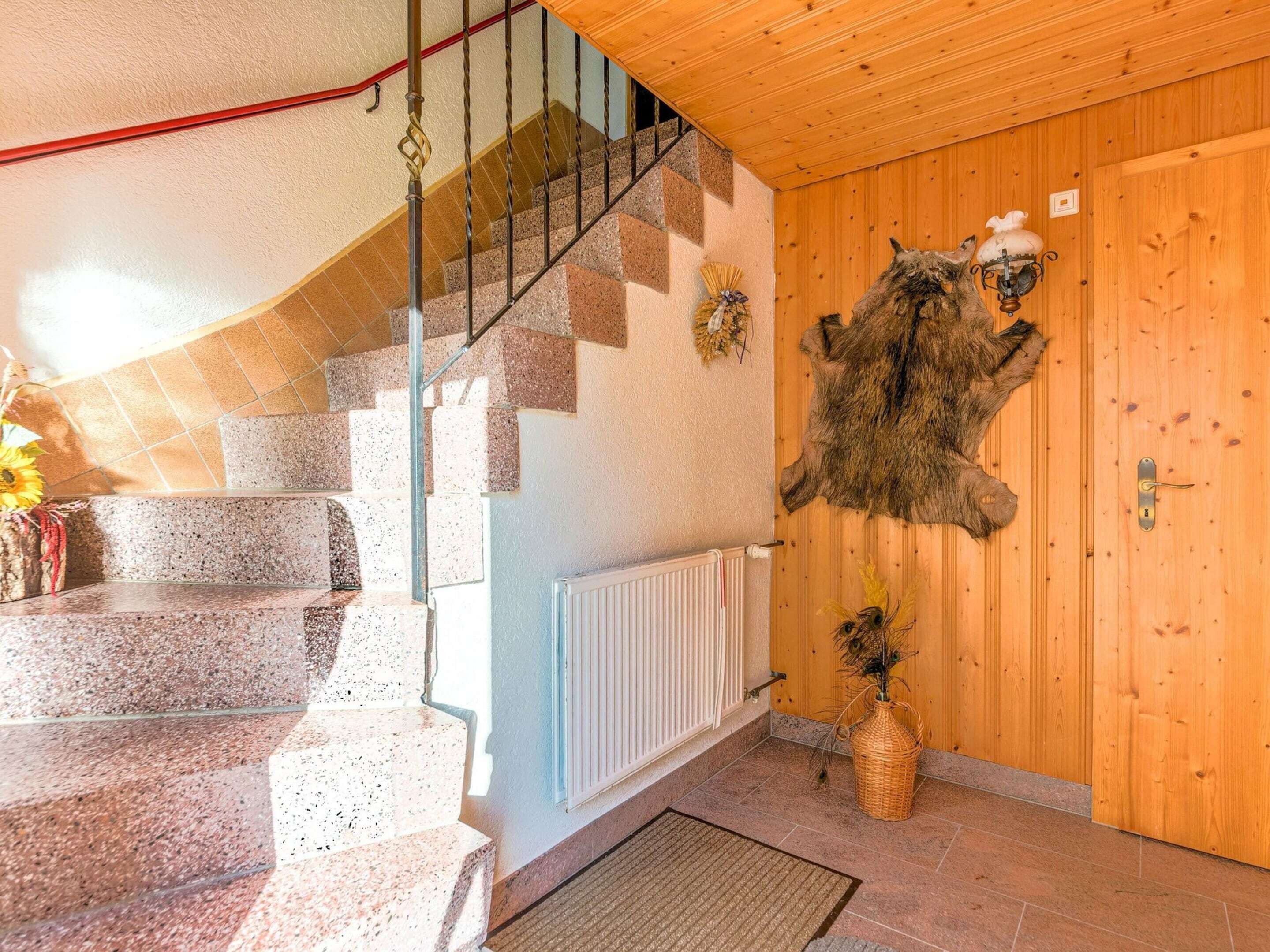 A staircase with granite steps leading to a wooden door with a fur coat hanging on it.