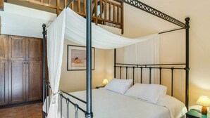 A four-poster bed with white linens, a wooden wardrobe, and a framed picture on the wall. - Villa in Crete With Private Pool & Views (Heraklion)
